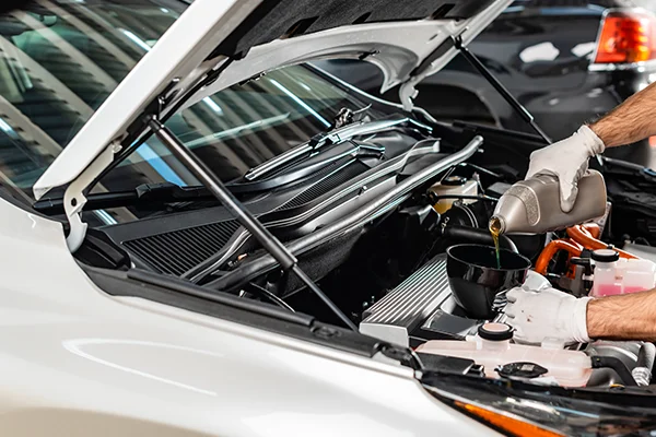 technician pouring oil into car