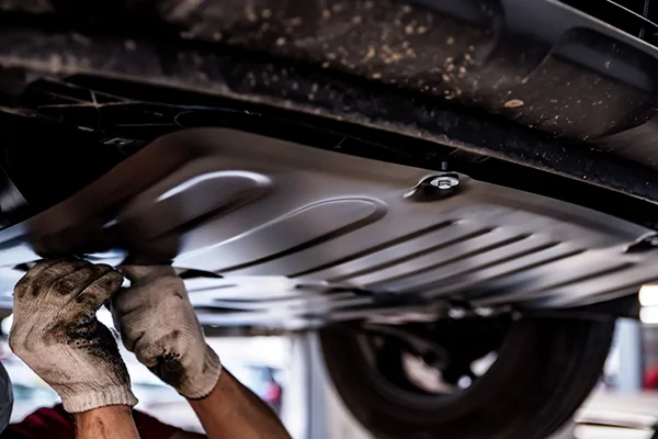 technician attaching belly pan on car
