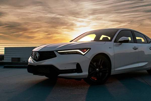 White Acura sedan parked in lot with sunset behind
